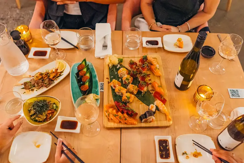 Tablée vue d’en haut : plateau de sushis, yakitoris et verres de vin