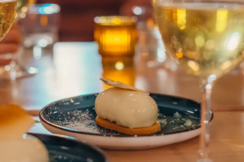 Dessert yuzu sur assiette bleue, verres de vin
